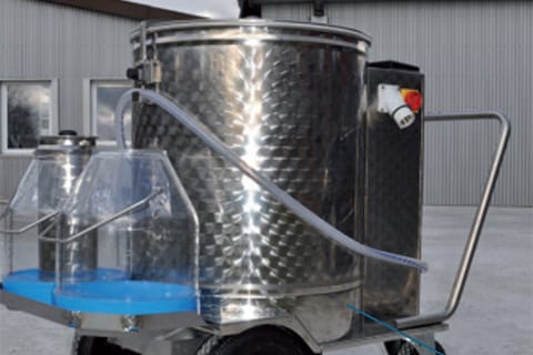 Mobile stainless steel vat or tank with a conical top, mounted on a cart with wheels and connected to a control box with dials and gauges. This equipment is likely used for food processing or brewing.